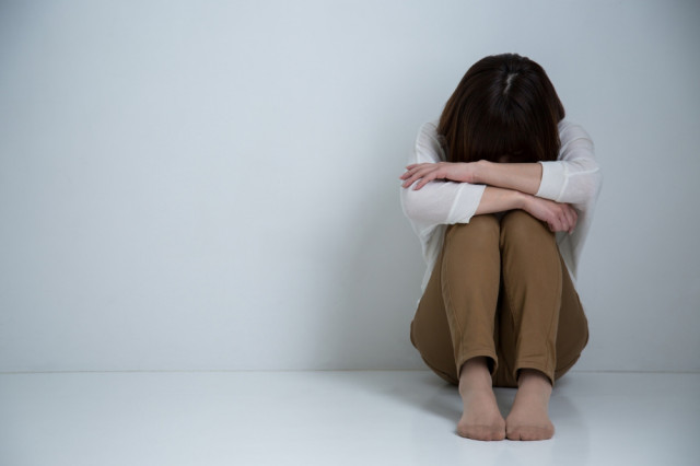 膝を抱える女性の写真